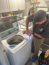 Technician inspecting a top load washer tub with a work light