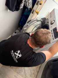 Technician reaching into a top load washer to check the drive system