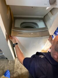 Technician checking the agitator shaft inside a top load washer