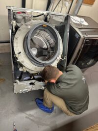 Front load washer tipped back to reach the drum and suspension