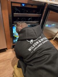 Technician servicing an under counter wine cooler in a Denver Metro kitchen