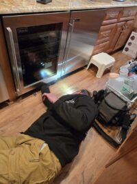 Technician working on a built in wine cooler with the door open