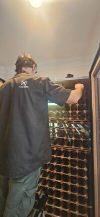Technician inspecting a walk in wine room cooling unit