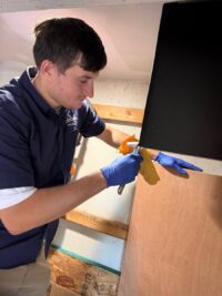 Technician handling a wine cooler door panel during a repair