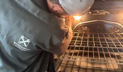 Wilson and Myers technician checking inside a lit oven cavity on a Denver Metro service call